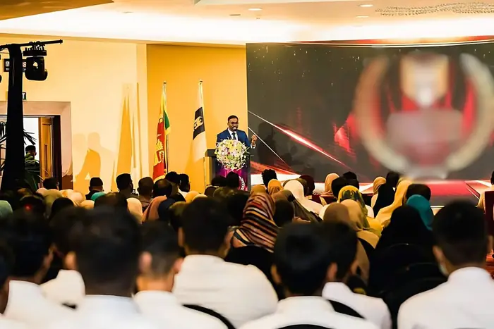 Mayantha addressing a packed auditorium from the stage